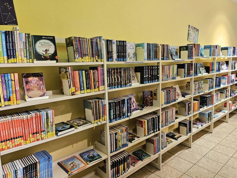 Ein Bücherregal in einer Bibliothek oder Buchhandlung, gefüllt mit einer Vielzahl von farbigen Büchern in verschiedenen Größen und Genres.