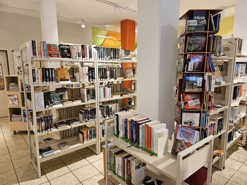 In einem hell beleuchteten Buchladen stehen mehrere Regale voller Bücher.